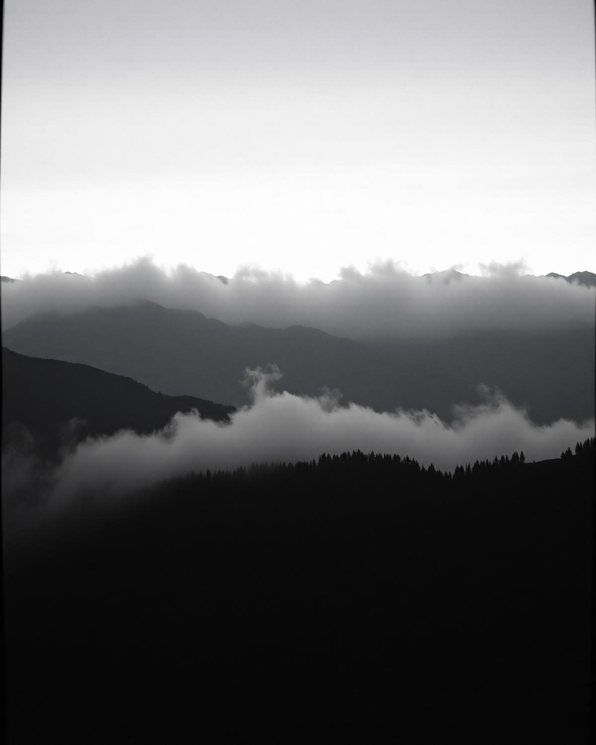 Fog rolling over dark mountain ridges at dawn